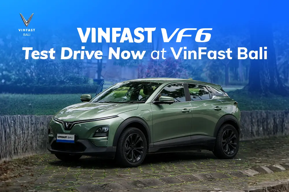 Sebuah mobil listrik SUV VinFast VF 6 berwarna hijau sedang parkir, dengan teks overlay "VINFAST VF6 Test Drive Now at VinFast Bali" di latar belakang biru.