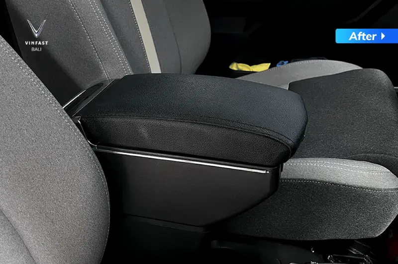 Tampilan interior kabin VinFast VF 3 dengan tambahan aksesoris konsol boks armrest (sandaran tangan) berbahan kulit sintetis hitam di antara jok depan.