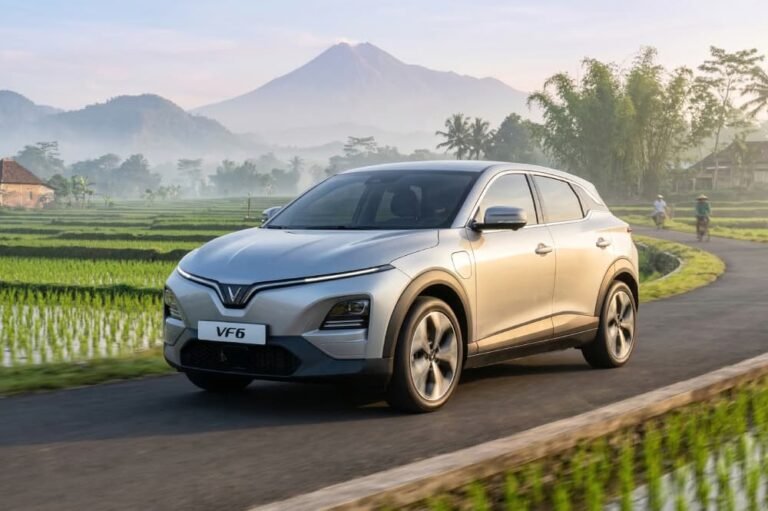 Mobil listrik VinFast VF 6 melintasi jalan pedesaan dengan latar belakang gunung saat mudik.